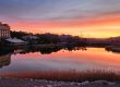 Sunset over Lake Las Vegas with homes and hotels in the background beneath a colorful evening sky.