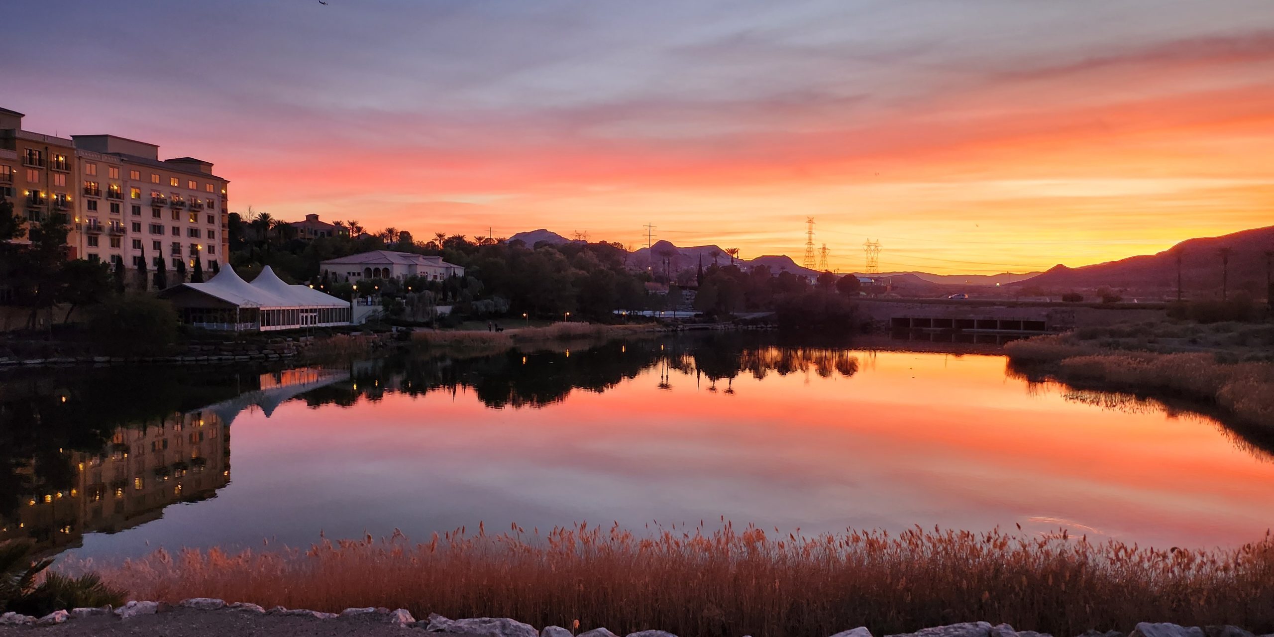 Sunset over Lake Las Vegas with homes and hotels in the background beneath a colorful evening sky.